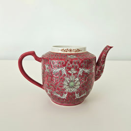 Red teapot with white floral patterns on a white background