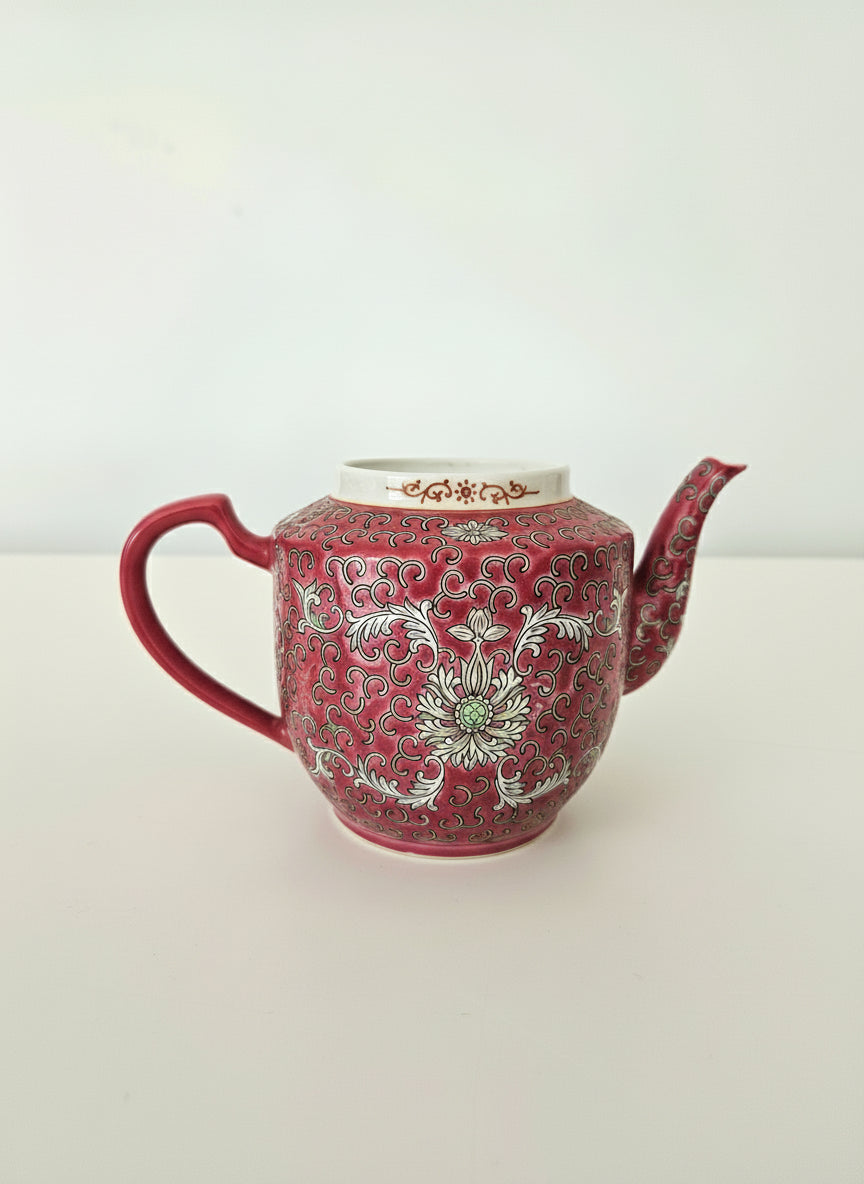 Red teapot with white floral patterns on a white background