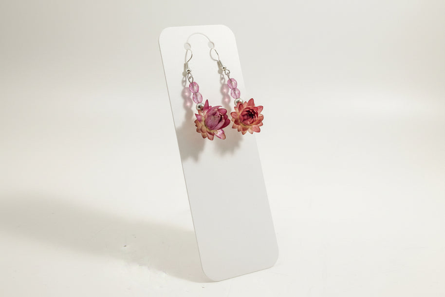 Pair of floral earrings on a clear stand against a light background