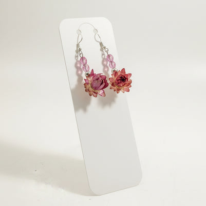 Pair of floral earrings on a clear stand against a light background