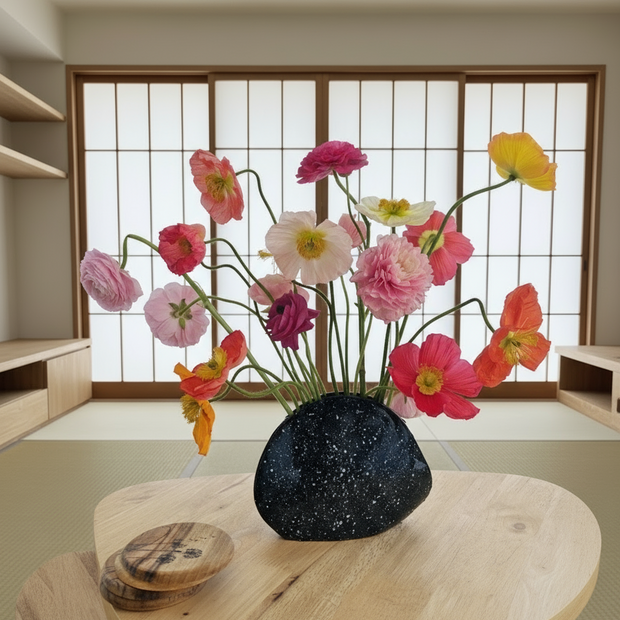 Decorative vase with colourful flowers on a wooden table in a room with sliding doors.