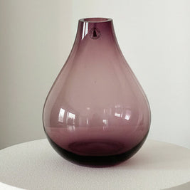 Purple glass vase on a white surface with a white background