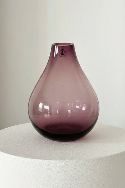 Purple glass vase on a white surface with a white background
