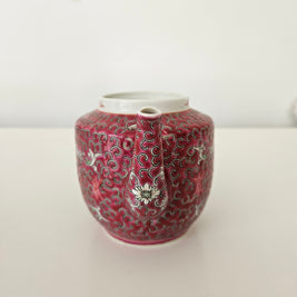 Decorative red teapot with intricate patterns on a white background