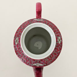 Ceramic red teapot with decorative pattern and handle on a light background