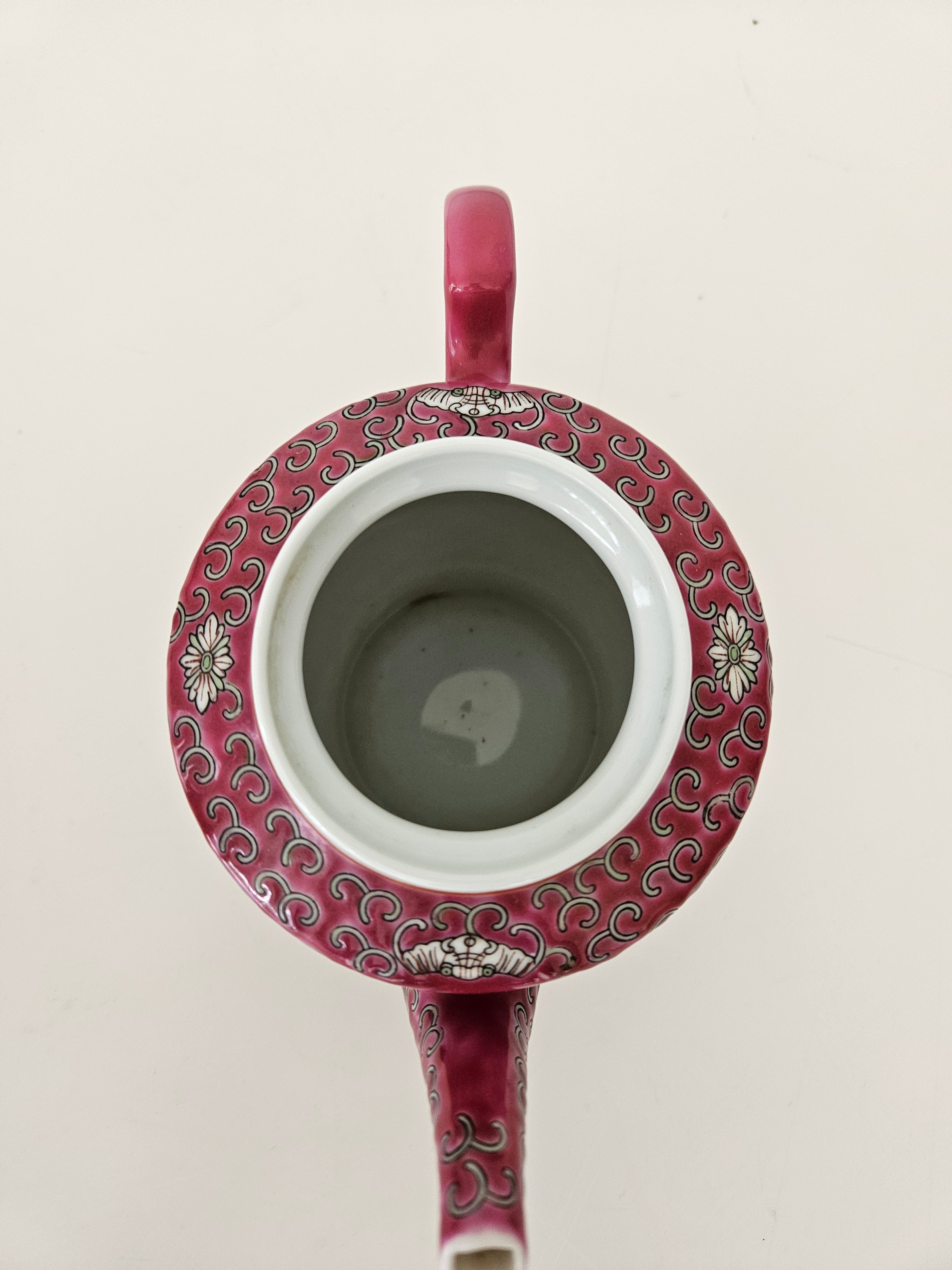 Ceramic red teapot with decorative pattern and handle on a light background