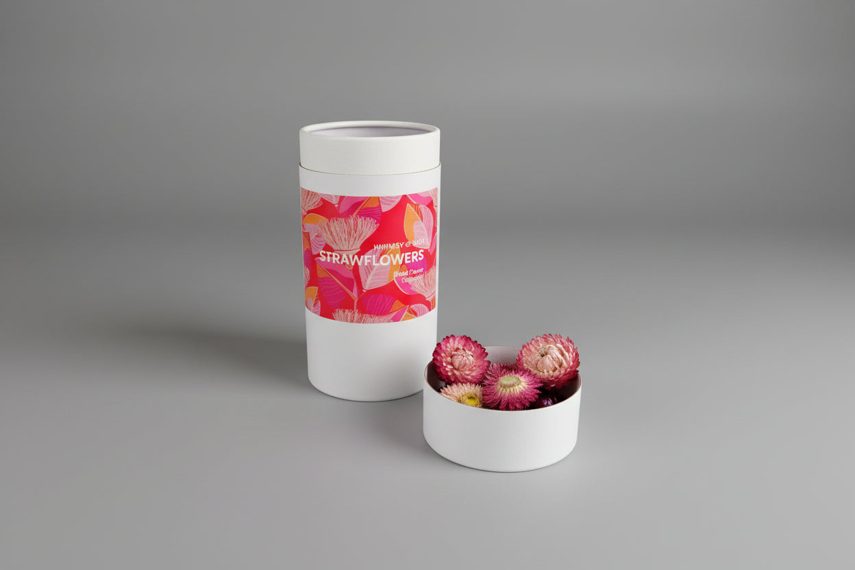 Container of strawflowers with a pink label on a white surface